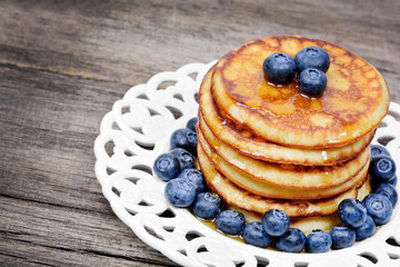 Stack of pancakes with fresh blueberry and maple syrup on plate