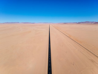 Stunning wide angle aerial drone view of the B4 desert road and a train line between L&uuml;deritz and Keetmanshoop in the Namib Naukluft Desert Park of Namibia, Africa. No curves on the road.