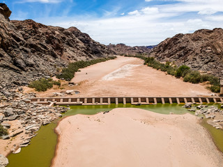 Stunning wide angle aerial drone view of the dry riverbed and an old dam with rests of water near...