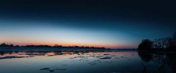 Panorama frozen river view at twilight and sunset with ice floes. Elbe Hamburg Northern Germany