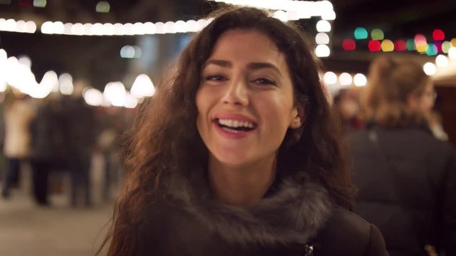 Portrait Of Smiling Woman Enjoying Christmas Market At Night