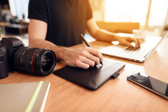 Close up freelancer bearded man drawing at laptop sitting at desk.