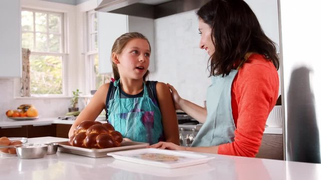 Mother and daughter smell freshly baked challah in kitchen