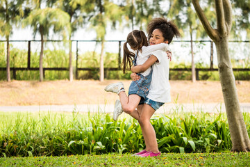 Naklejka na ściany i meble Cheerful little girls hugging in a park.