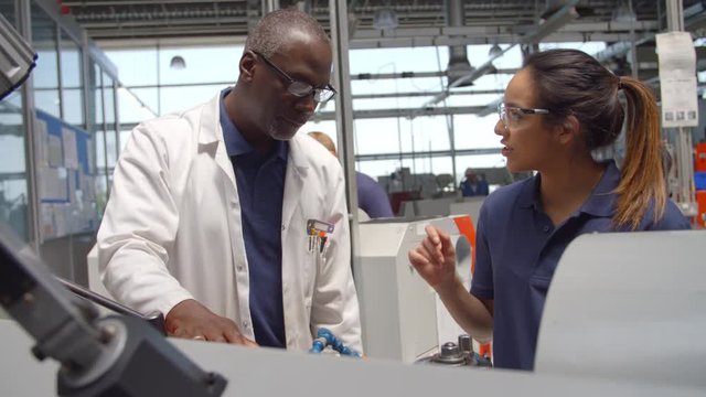 Engineer Teaching Apprentice How To Use Machine In Factory