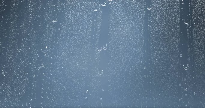 rain drops falling down on glass blue background, water droplets on window glass