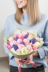 Sunny spring morning. Young happy woman holding a beautiful bunch of pink and violet hyacinths in her hands. Present for a smiles girl. Flowers bouquet.
