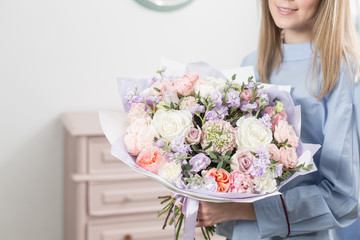 Sunny spring morning. Young happy woman holding a beautiful luxury bouquet of mixed flowers. the work of the florist at a flower shop