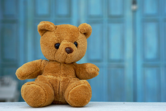 The Lonely teddy bear sits in front of a light blue wooden background