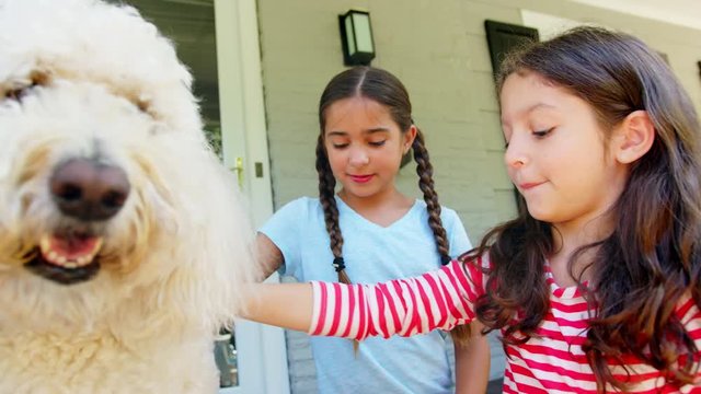 Two Girls Stroking Family Dog On Porch Of House