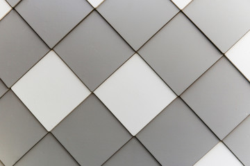 Gray and white tiles arranged on the wall in diagonal pattern. Background image.