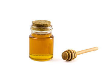 Honey in jar and wooden honey dipper isolated on white background with clipping path.