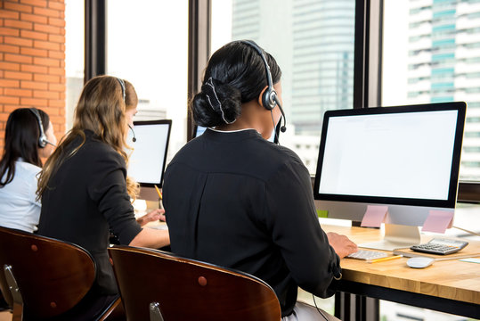 Telemarketing businesswomen wearing headphones working on computers