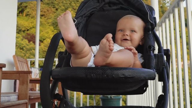 little baby boy smiling and waving in stroller . Childhood dreams and memories.