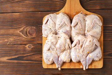 Raw quails in spices on a wooden background. Close-up.