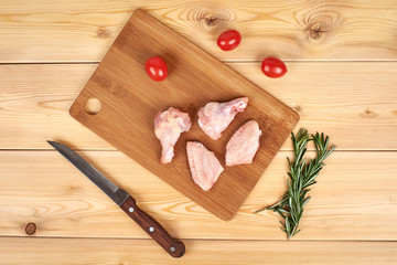 Raw chicken wings on cutting board, wooden background