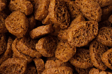 Brown slices rye croutons as background, top view, closeup.