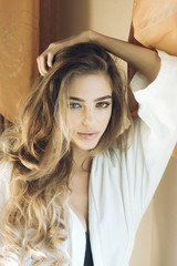 Fototapeta premium Girl with mysterious face and long curly hair in bathrobe.