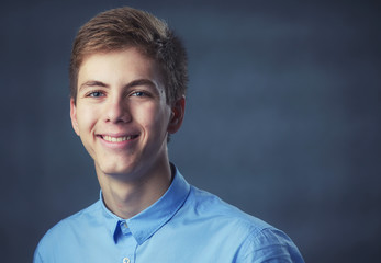 young man on grey background, student in blue shirt