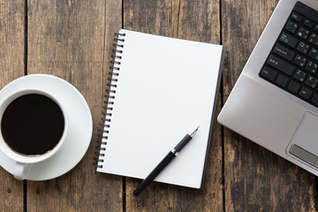 empty notebook with coffee cup and computer on wooden table ,top view