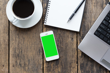 smart phone blank screen with cup coffee and computer on old wooden table top view.