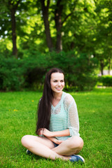 Young smiling woman sitting on grass.