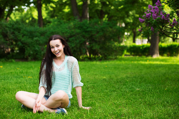 Fototapeta premium Smiling beautiful young woman sitting on grass.