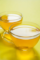 Two cups of herbal tea on a bright yellow background. Pastel colors. Minimalism. Place for text