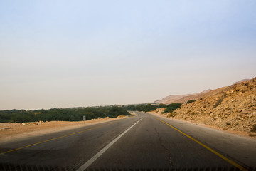 Desert highway and mountains through car window not far from Dead sea