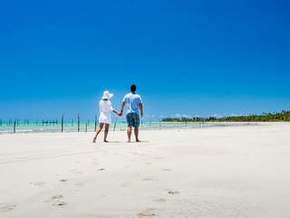 couple walking along beach with view on a summer day