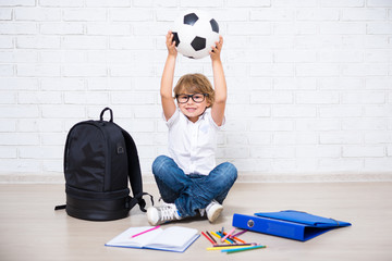 little boy in glasses with school tools and soccer ball