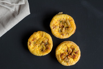 Quiche Lorraine backround, top view of three mini tartlets closeup on black background with space for text.