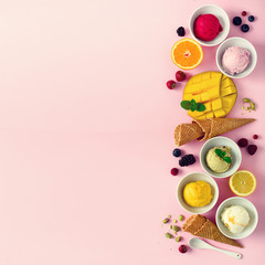 Top view red, pink, yellow, green, white ice cream balls in bowls, waffle cones, berries, orange, mango, pistachio, pink shabby chic background. Ice-cream colorful collection, flat lay, summer concept