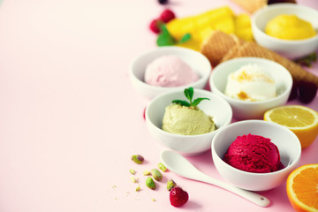 Red, pink, yellow, green, white ice cream balls in bowls, waffle cones, berries, orange, mango, lemon, mint, pistachio, pink shabby chic background. Ice-cream colorful collection, summer concept