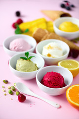 Red, pink, yellow, green, white ice cream balls in bowls, waffle cones, berries, orange, mango, lemon, mint, pistachio, pink shabby chic background. Ice-cream colorful collection, summer concept