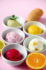 Red, pink, yellow, green, white ice cream balls in bowls, waffle cones, berries, orange, mango, lemon, mint, pistachio, pink shabby chic background. Ice-cream colorful collection, summer concept