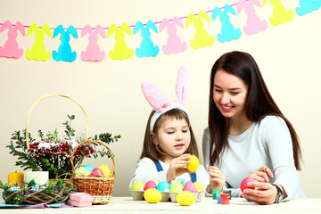 Mother and little daughter coloring Easter eggs