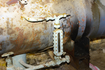 Old and rusty shut-off valve and taps from equipment at an abandoned and destroyed factory amid chaos. Destruction and vandalism. Ukraine.