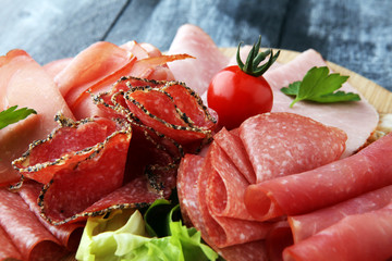 Food tray with delicious salami, pieces of sliced ham, sausage, tomatoes, salad and vegetable - Meat platter with selection