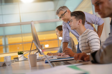 Teacher with students in apprenticeship attending computing class