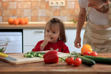 Cute little girl testing vegetable on the kitchen