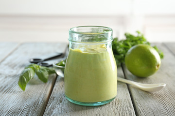 Obraz na płótnie Canvas Tasty creamy lime mustard sauce for fish taco in glass jar on kitchen table