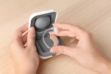 Woman holding hearing aid, closeup