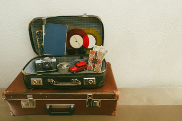 Open leather travel valises or old suitcase with camera, toy car, vintage vinyl records, passport, money , sunglasses and old books Close up, travel photo