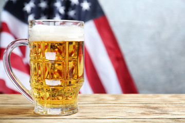 Glass of beer on table against American flag background