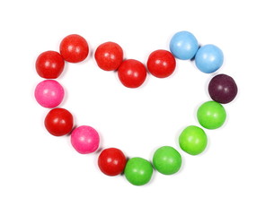 Colorful candies in heart shape isolated on white background, top view
