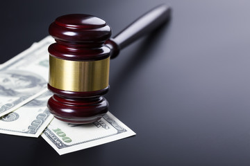 Wooden judge gavel on hundred dollar banknotes over black background