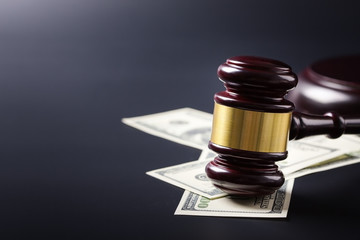 Wooden judge gavel on hundred dollar banknotes over black background