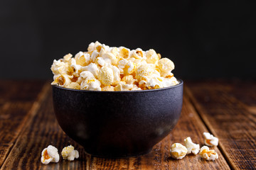 A bowl with popcorn on a wooden background.