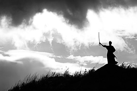 Silhouette black and white photo warrior with sword on the mountain